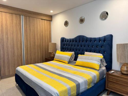 a bedroom with a blue bed with yellow and white stripes at Departamento a pie de playa en Camino al Mar in Mazatlán