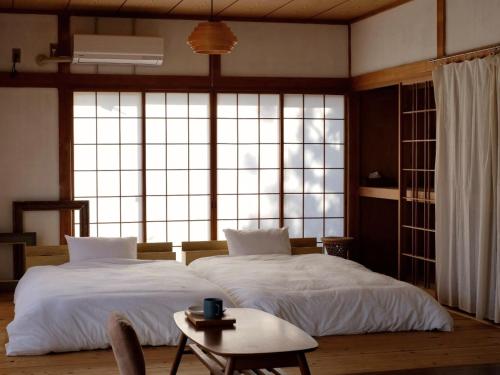 two beds in a room with a large window at 海の見える高台に佇む隠れ家宿 #貸別荘 #一棟貸切 #グループや家族旅行におすすめ #テラスで海を眺めながらBBQ #屋内でもBBQ可 #BBQグリル付 #大洗 #鉾田 #umibe in Hokota