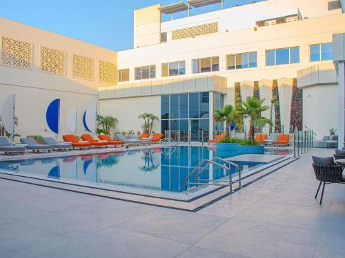 a hotel with a swimming pool in front of a building at Novotel World Trade Centre Dubai in Dubai
