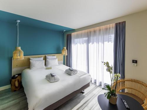a bedroom with a large white bed with a blue wall at Novotel Monte-Carlo in Monte Carlo