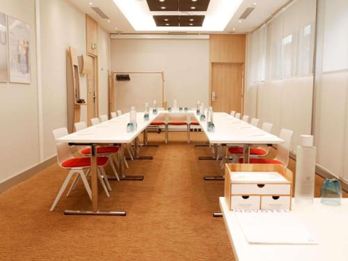 a conference room with white tables and red chairs at Novotel Monte-Carlo in Monte Carlo
