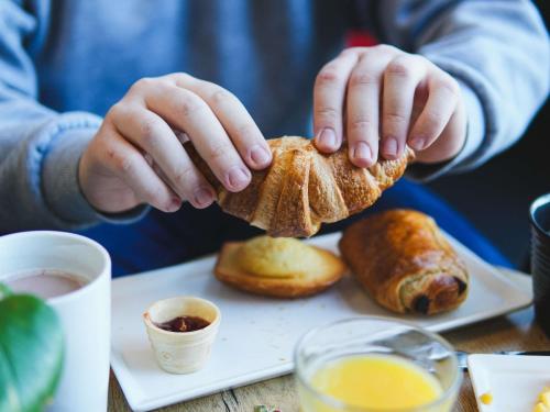 a person holding a piece of bread on a plate at ibis Caen Porte De Bretagne in Bretteville-sur-Odon