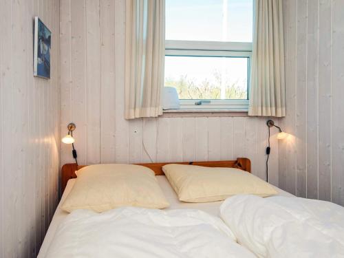 a bed with two pillows in a bedroom with a window at Holiday Home near Loddenhoj Beach in Brøde
