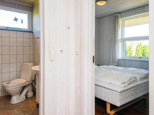 a bedroom with a bed and a toilet and a window at Holiday Home near Loddenhoj Beach in Brøde