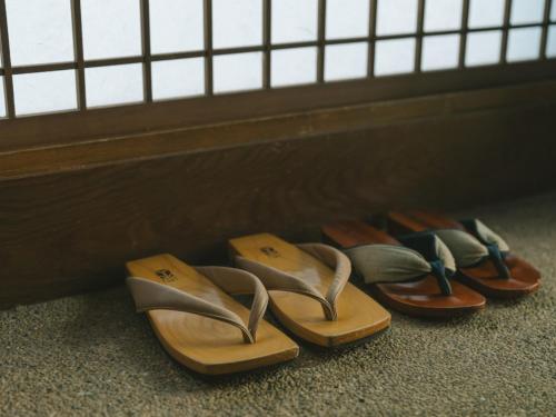 four pairs of shoes are lined up against a wall at Ujosouan in Kyotango