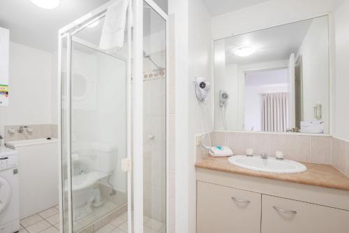 a white bathroom with a sink and a shower at Island Beach Resort in Gold Coast