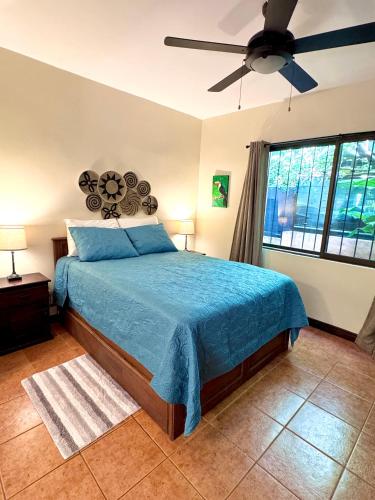 a bedroom with a blue bed and a ceiling fan at Tiny Paradise Ground Floor Studio in Coco