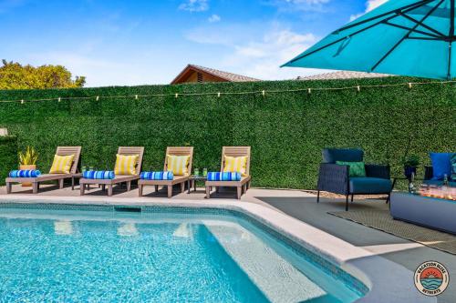 a group of chairs and an umbrella next to a swimming pool at 4BR Chula Vista Getaway Splash, Play & Game! in Chula Vista