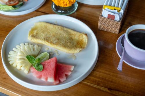 a plate with a piece of bread and fruit on a table at Pondok Tis Bisma in Ubud