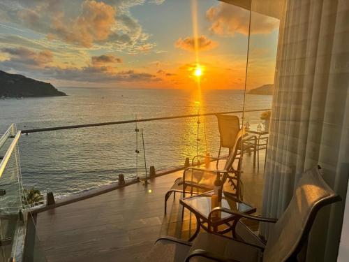 a balcony with chairs and a sunset on the ocean at Departamento a pie de playa en Camino al Mar in Mazatlán