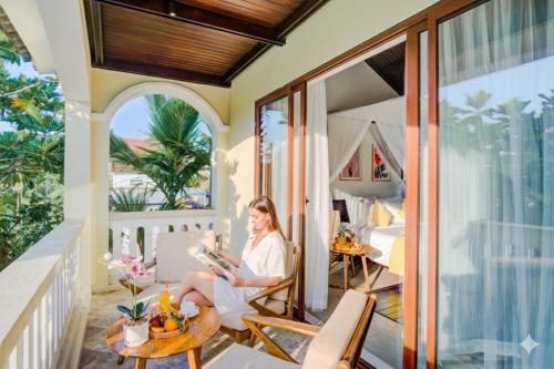 a woman sitting on the balcony of a villa at Én Retreat Hoi An in Hoi An