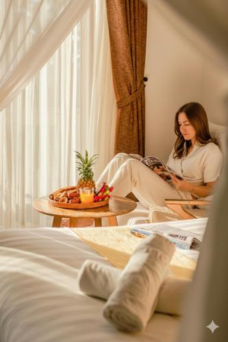 a woman sitting in a chair in a hotel room at Én Retreat Hoi An in Hoi An