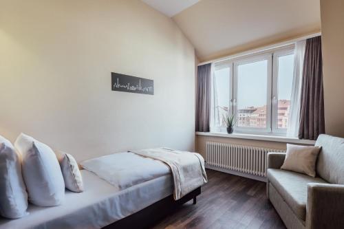 a bedroom with a bed and a couch and a window at Garner Hotel Berlin - Charlottenburg, an IHG Hotel in Berlin