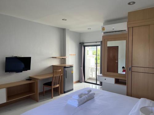 a bedroom with a bed and a desk and a television at J2 Airport Mansion in Thalang
