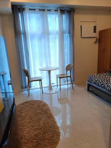 a living room with a table and chairs and a bed at Mivela Residences in Cebu City