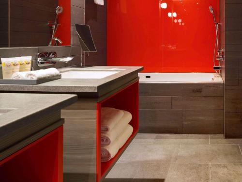 a bathroom with red cabinets and a sink and a tub at Pullman London St Pancras in London