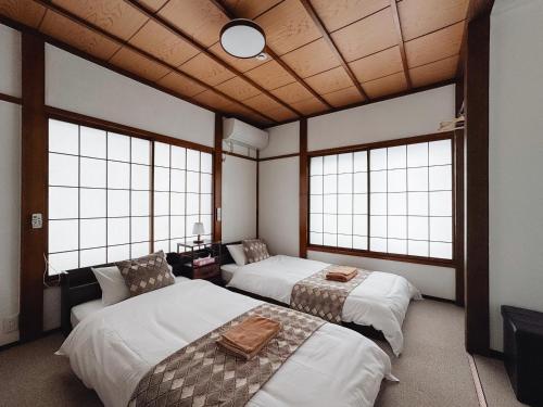two beds in a room with windows at 雪场缆车站旁-汤泽雪の宿-Ski IN Ski OUT-全新装修 in Seki