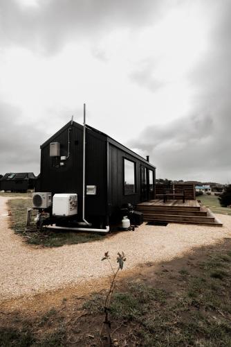 a black tiny house sitting on top of a field at Swell At Cape Bridgewater in Cape Bridgewater