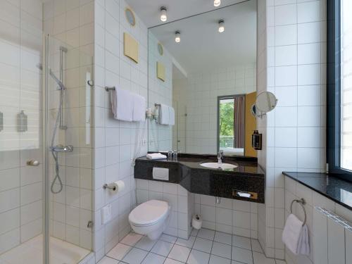 a bathroom with a toilet and a shower and a sink at Mercure Hotel Aachen Am Dom in Aachen