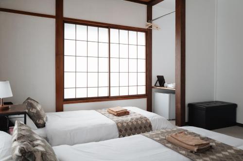 a bedroom with two beds and a large window at 雪场缆车站旁-汤泽雪の宿-Ski IN Ski OUT-全新装修 in Seki
