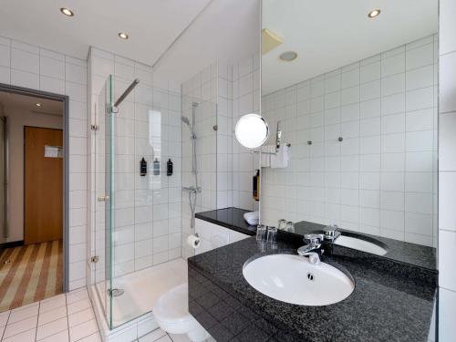 a bathroom with a sink and a shower at Mercure Hotel Aachen Am Dom in Aachen