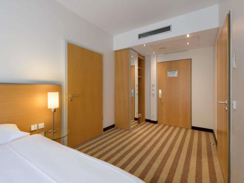 a hotel room with a bed and a hallway at Mercure Hotel Aachen Am Dom in Aachen