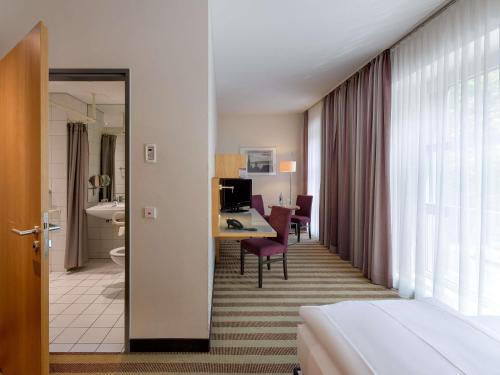 a hotel room with a bed and a table and a desk at Mercure Hotel Aachen Am Dom in Aachen