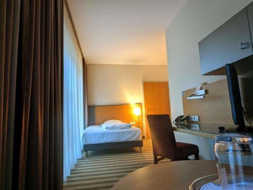 a hotel room with a bed and a table at Mercure Hotel Aachen Am Dom in Aachen