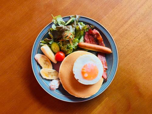 a plate of food with an egg and a salad at Guesthouse HOALOHA 4 SEASONS in Chino