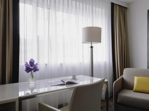a room with a desk with a lamp and a chair at Pullman Berlin Schweizerhof in Berlin