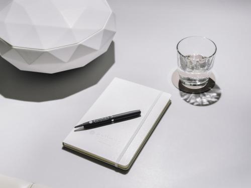 a pen sitting on top of a notebook next to a glass at Pullman Berlin Schweizerhof in Berlin