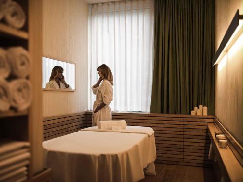 a woman standing next to a bed in a room at Pullman Berlin Schweizerhof in Berlin