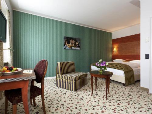 a hotel room with a bed and a table and a chair at Mercure Grand Hotel Biedermeier Wien in Vienna