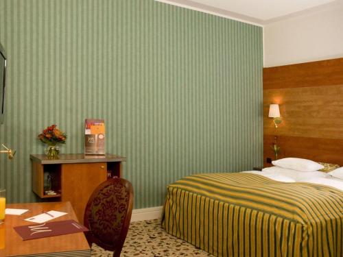 a hotel room with a bed and a table at Mercure Grand Hotel Biedermeier Wien in Vienna
