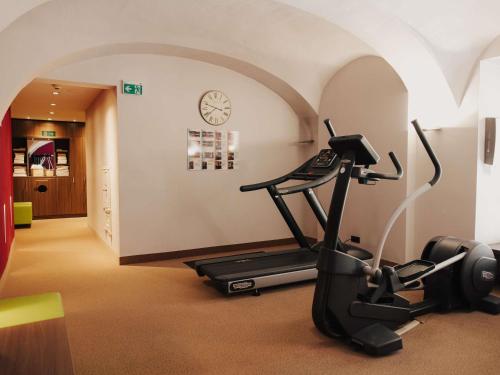 a room with a gym with a treadmill and a clock at Mercure Grand Hotel Biedermeier Wien in Vienna