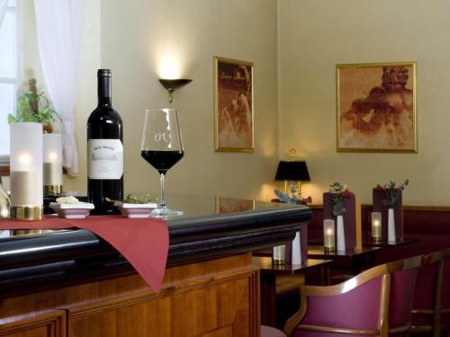 a bottle of wine sitting on a bar with a glass at Mercure Grand Hotel Biedermeier Wien in Vienna