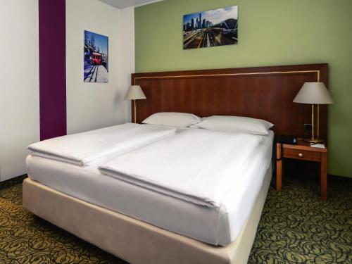 a bedroom with a large white bed with a wooden headboard at Hotel Mercure Wien Westbahnhof in Vienna