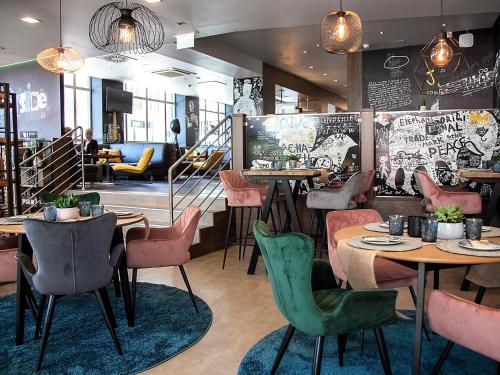 a restaurant with tables and chairs and a staircase at Hotel Mercure Wien Westbahnhof in Vienna