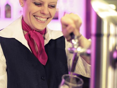 a woman is smiling while holding a wine glass at Hotel Mercure Wien Westbahnhof in Vienna