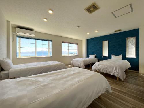 a bedroom with three beds and a blue wall at 貸別荘 波音と朝日 namine to ASAHI in Miyazu