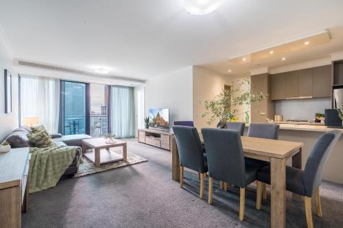 a living room with a dining table and a kitchen at StayCentral - Cityviews on City Road Southbank in Melbourne