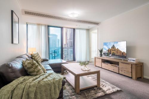 a living room with a couch and a tv at StayCentral - Cityviews on City Road Southbank in Melbourne