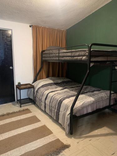 a bedroom with two bunk beds and a green wall at Casa Tacambaro, minutes from the Consulate in Manuel F. Martínez