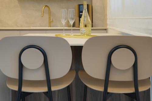 two white chairs sitting next to a counter with wine glasses at לוי-קיישן מגוון דירות גן ופנטהאוזים וסוויטות נוף ברחוב הצנחנים in Tiberias