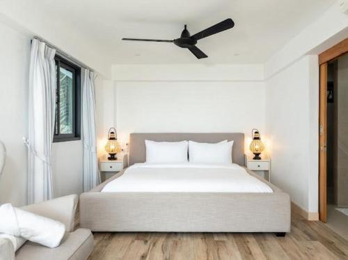 a bedroom with a large white bed with a ceiling fan at Tahiana Villa in Haad Tian