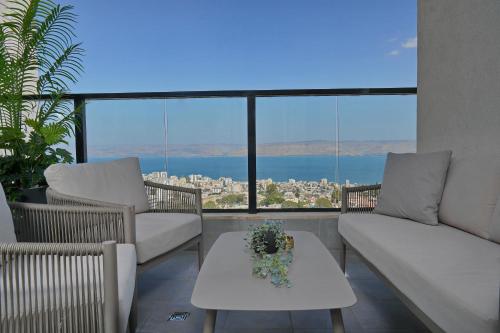 a balcony with couches and a table with flowers on it at לוי-קיישן מגוון דירות גן ופנטהאוזים וסוויטות נוף ברחוב הצנחנים in Tiberias
