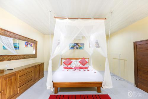 a bedroom with a bed with a mosquito net at Pondok Kutuh Guest House in Ubud