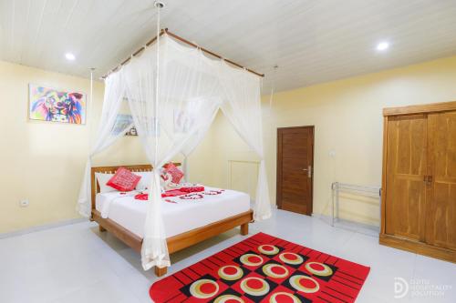 a bedroom with a canopy bed and a red rug at Pondok Kutuh Guest House in Ubud