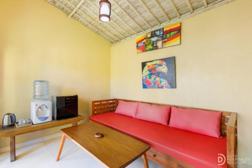 a living room with a red couch and a tv at Pondok Kutuh Guest House in Ubud