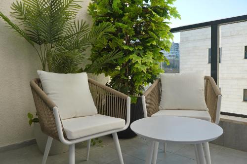 two chairs and a table on a balcony with plants at לוי-קיישן מגוון דירות גן ופנטהאוזים וסוויטות נוף ברחוב הצנחנים in Tiberias